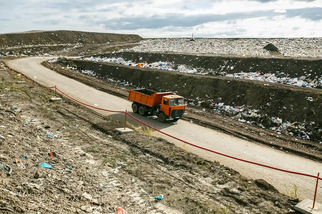 Truck driving through landfill site filled with waste—emphasizing Kadam Colors’ goal to cut fabric waste via sustainable dyeing.