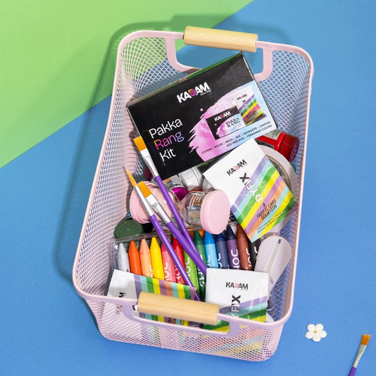 Kadam Pakka Rang Kit with DyFix sachets in a pink basket filled with crayons, brushes, and DIY craft supplies on colorful background.