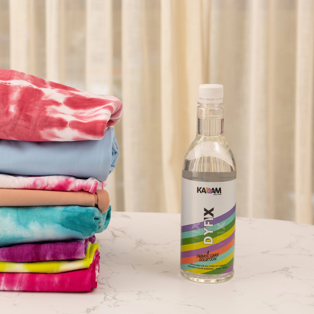 Kadam DyFix liquid placed beside folded dyed fabrics—protects colors and prevents bleeding after DIY fabric dyeing.