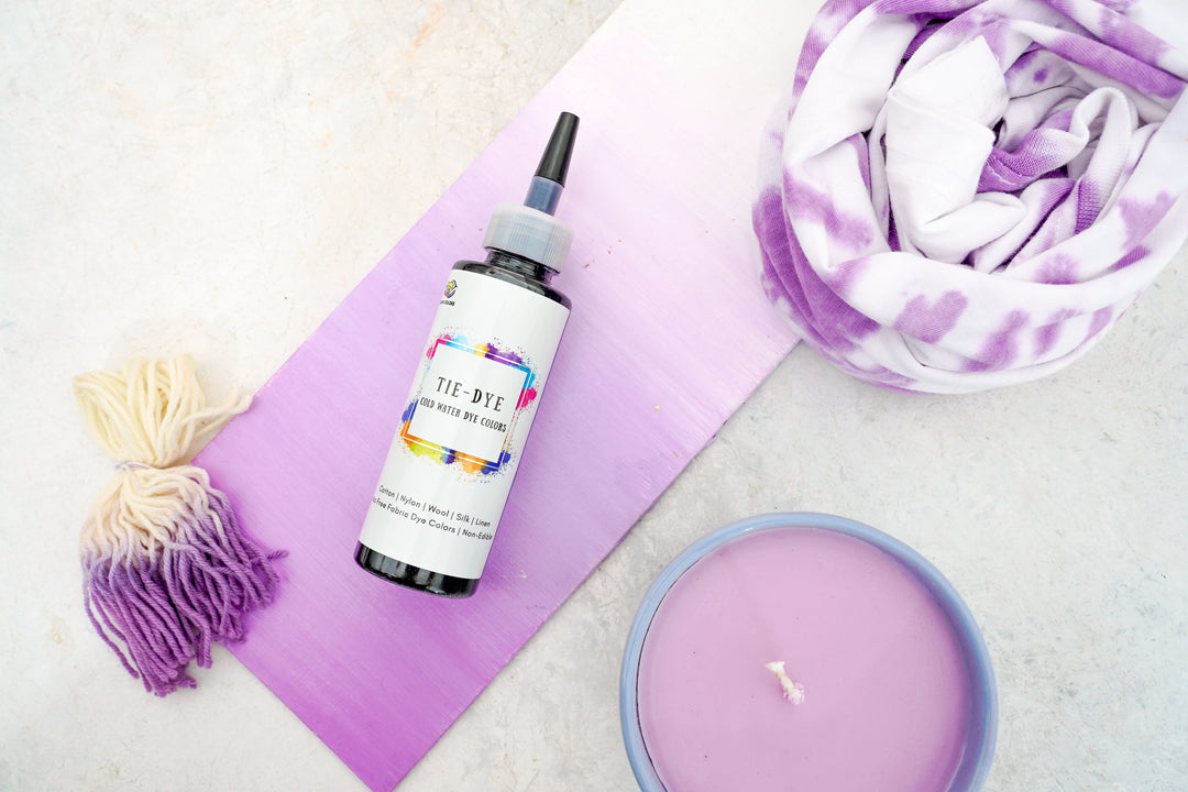 Purple Kadam Colors Tie-Dye bottle with yarn, scarf, and candle—cold water fabric dye for vibrant, long-lasting color.
