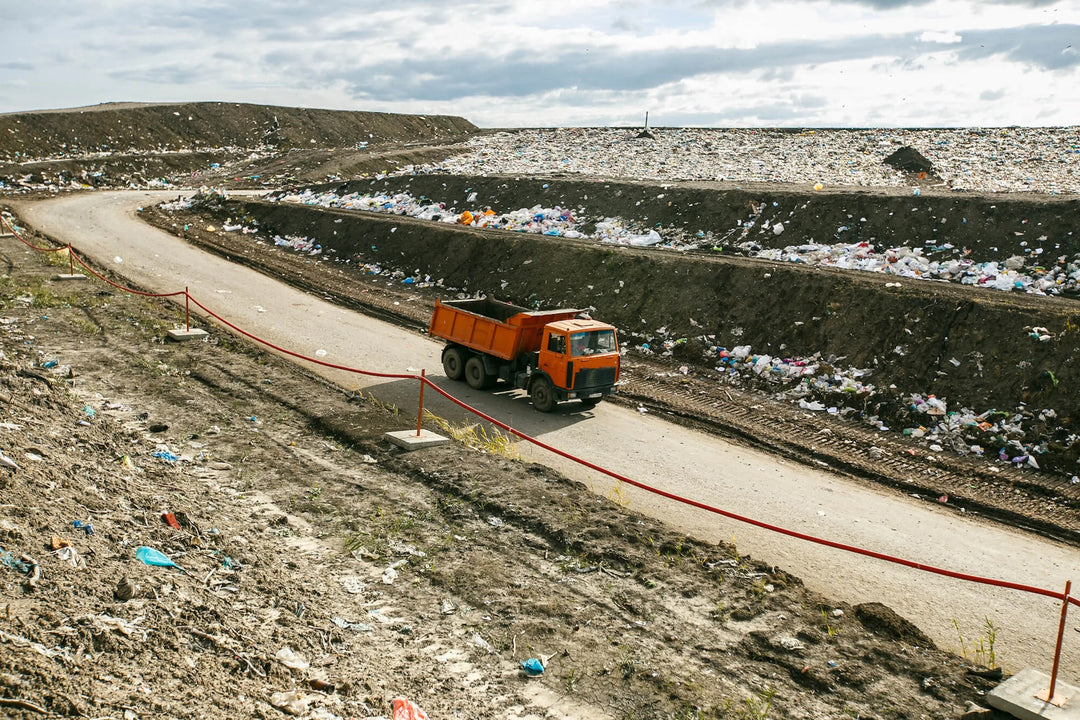 Truck driving through landfill site filled with waste—emphasizing Kadam Colors’ goal to cut fabric waste via sustainable dyeing.